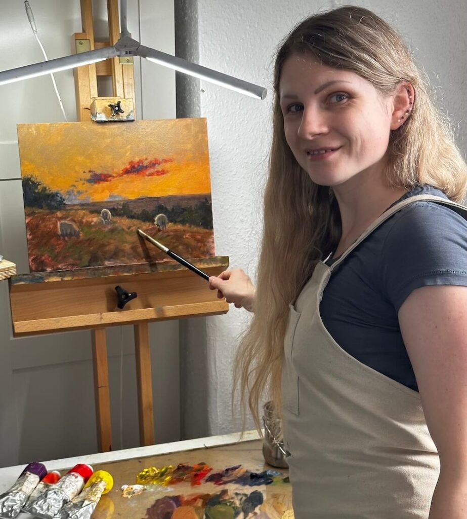 Greta Vilidaite in the middle of painting Quiet Under Red Skies oil painting, preselected for chelsea art society exhibition 2024.